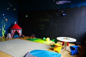 Ein Kinderspielzimmer mit einer Tafelwand, einem Spielzelt und verschiedenen Spielsachen.