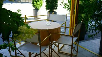 A round table with a white tablecloth and four chairs with gold frames.