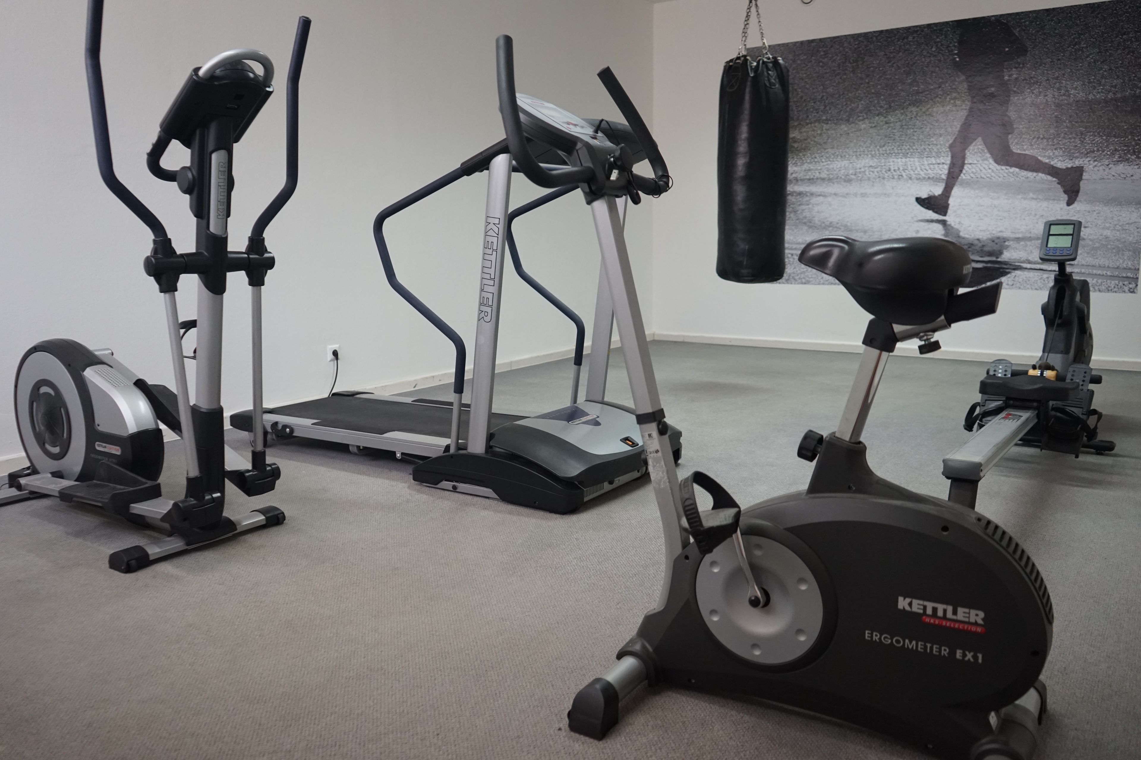 Un gimnasio con cintas de correr, elípticas y bicicletas estáticas.