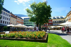 Un patio con un jardín de flores, mobiliario exterior y un hotel llamado "Altstadthotel Eck" al fondo.