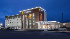 A La Quinta hotel with a modern design, featuring a prominent logo, a covered entrance, and a parking lot with several cars. - La Quinta Inn & Suites by Wyndham Madera (Madera)