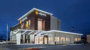 A La Quinta hotel with a modern design, featuring a prominent entrance and a covered parking area.