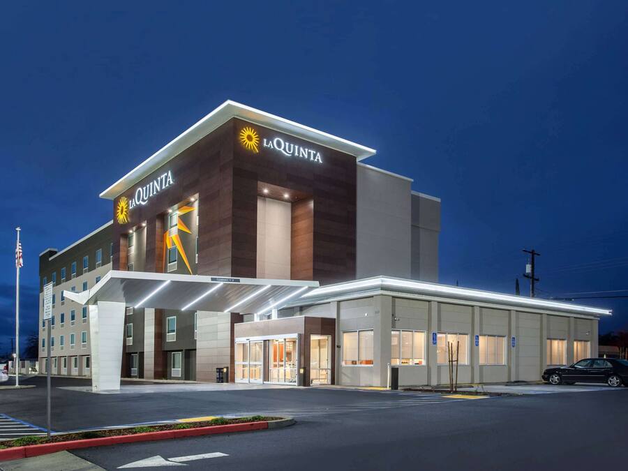 A La Quinta hotel with a modern design, featuring a prominent entrance and a covered parking area.