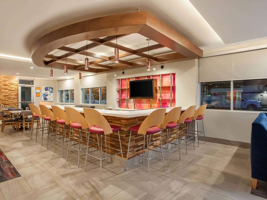A modern kitchen with a central island, bar stools, and a large window.