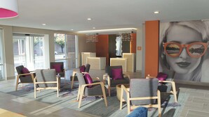 A lobby with seating areas, a reception desk, and a large wall mural. - La Quinta Inn & Suites by Wyndham Madera (Madera)