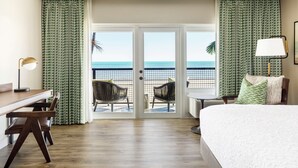 Habitación de hotel con balcón, cama, escritorio y dos sillas.