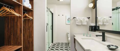 Un baño moderno con tocador de madera, un espejo grande y un suelo con estampado geométrico.