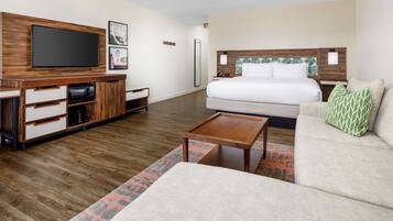 A modern hotel room with a large bed, a flat-screen TV, a wooden entertainment unit, and a small coffee table.