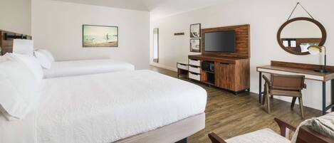 Une chambre d’hôtel avec deux lits, un bureau, une chaise, une télévision et un grand miroir.