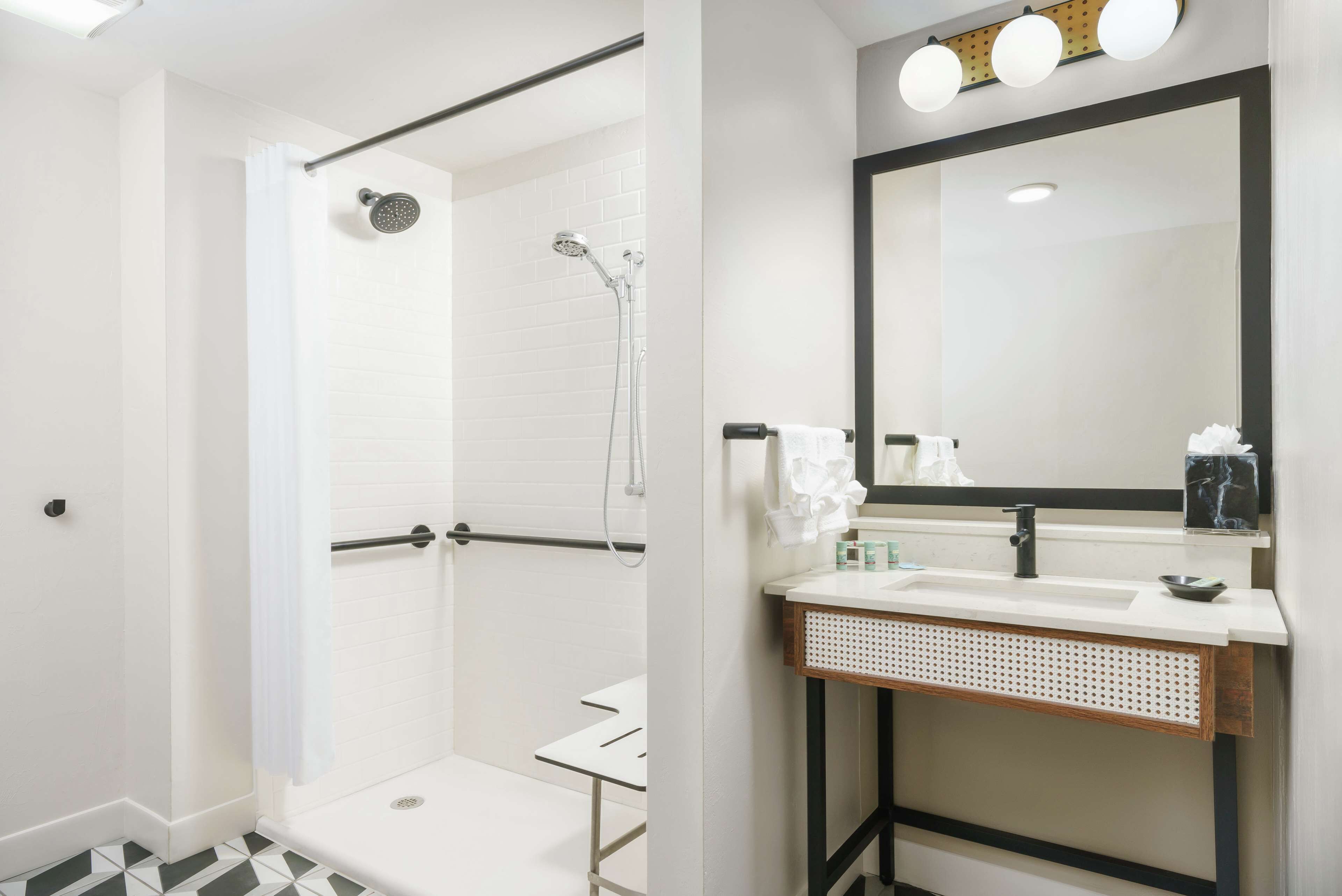 Un bagno moderno con doccia a filo pavimento, un mobile lavabo con specchio e un lavandino.