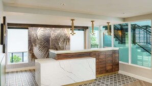 Una cocina moderna con una isla de mármol, armarios de madera e iluminación colgante.