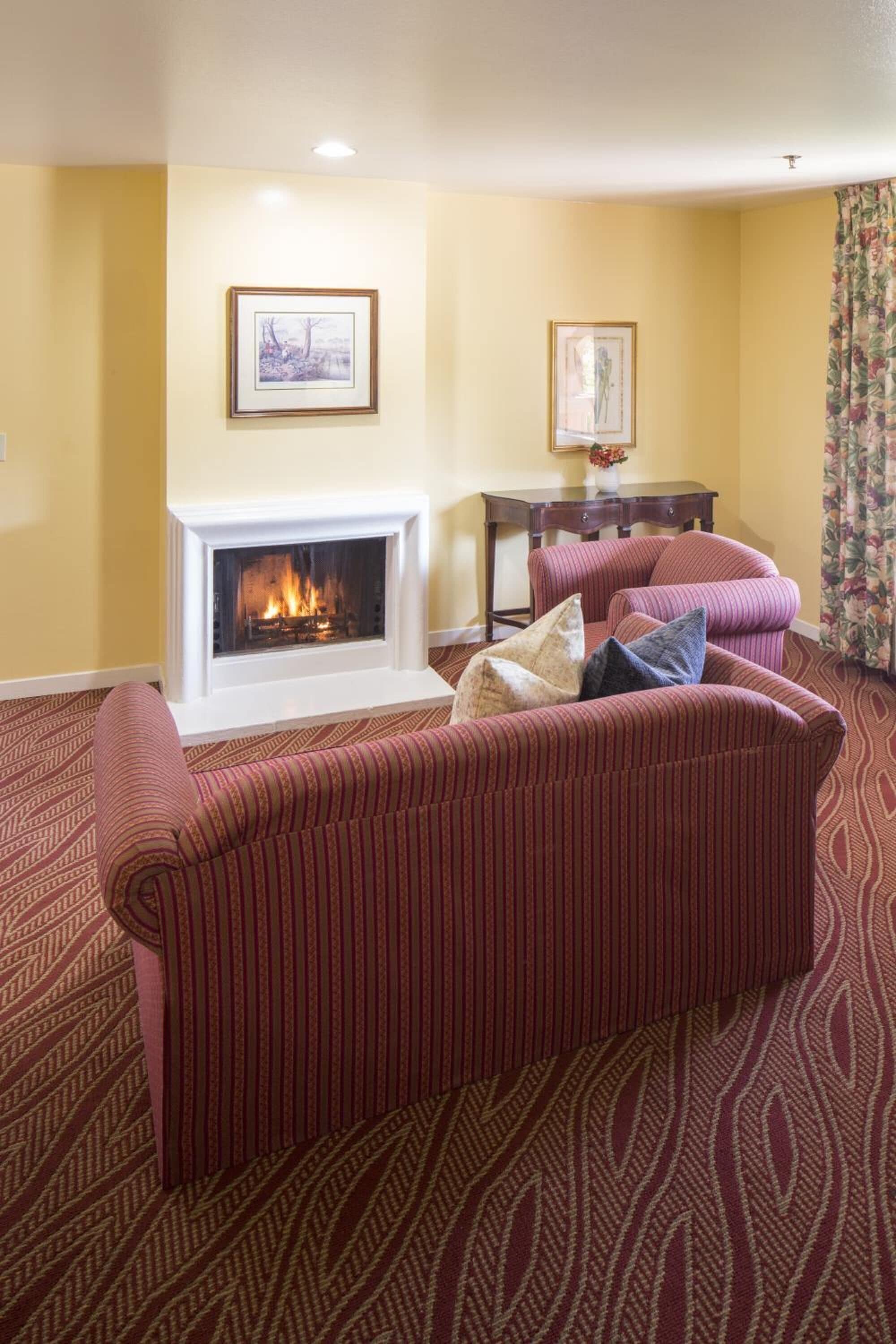 Una sala de estar con chimenea, un sofá y una mesa con un florero.