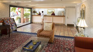 Un hall d’hôtel comprenant un comptoir d’accueil, un canapé, une table basse et un tapis à motifs.