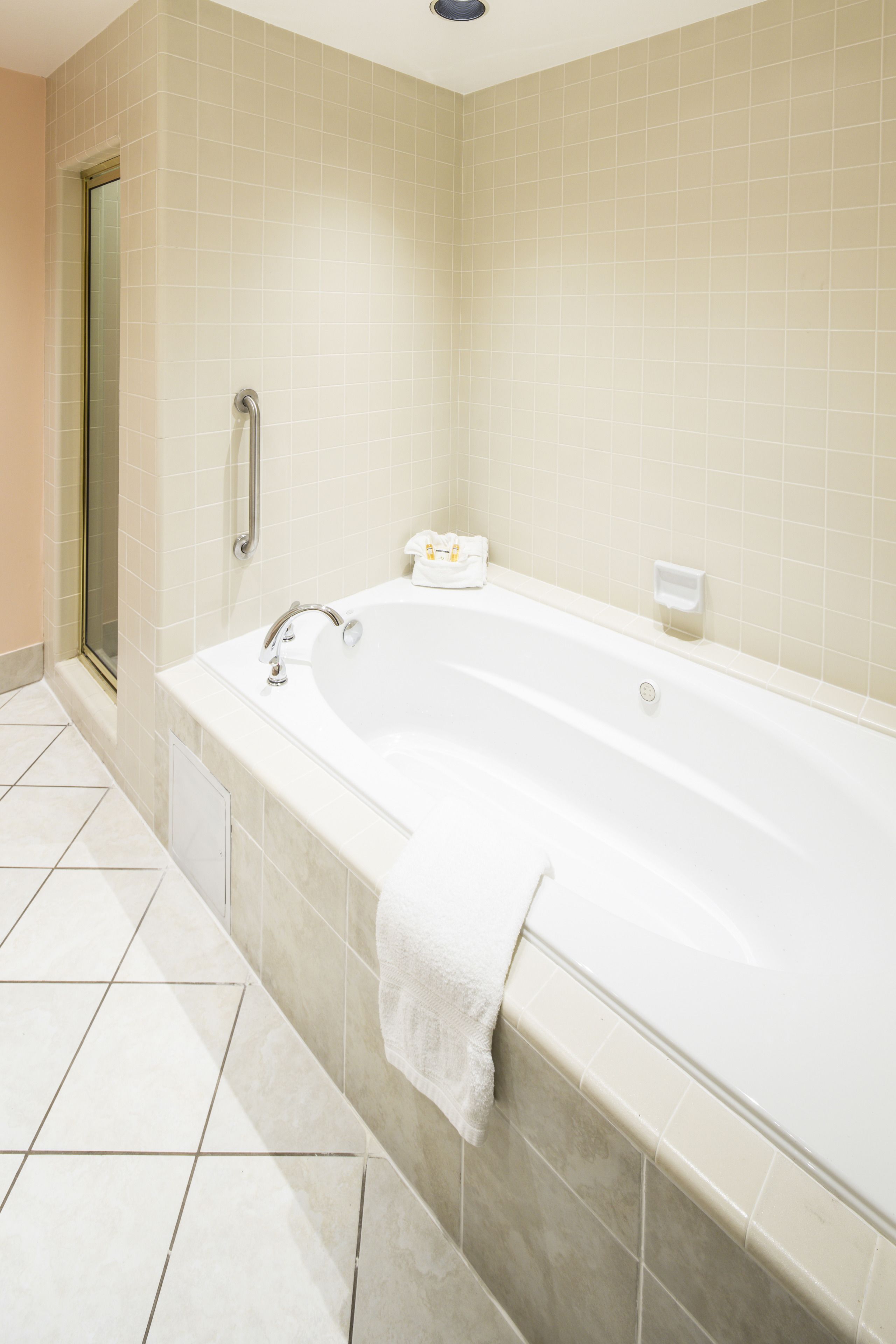 A modern bathroom with a large bathtub, a glass shower enclosure, and a tiled floor.
