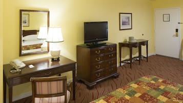 A hotel room with a bed, a desk with a telephone, a television, a chair, and a dresser.