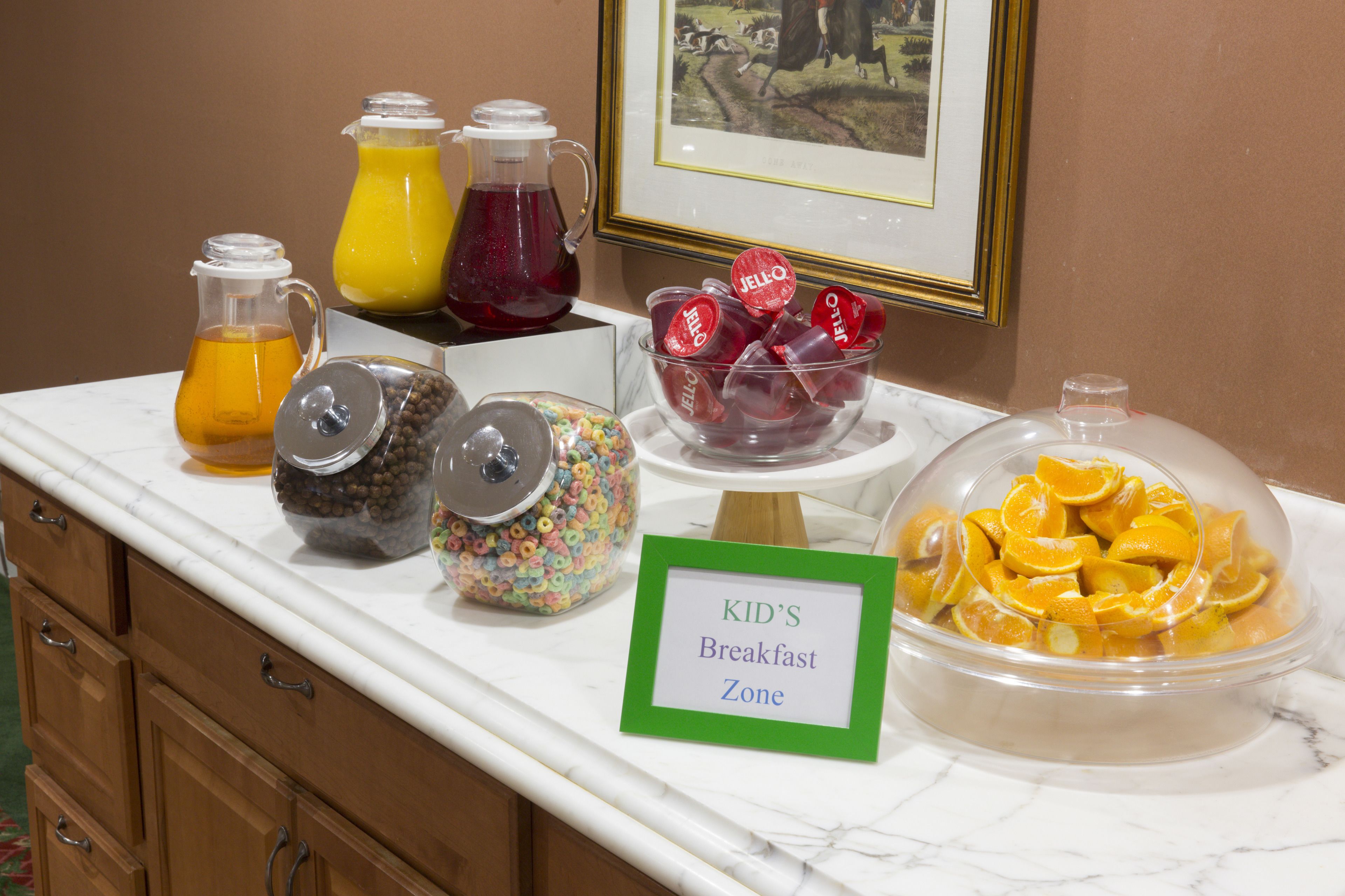 A breakfast area with a sign indicating it's a kid's zone, featuring various drinks and snacks.