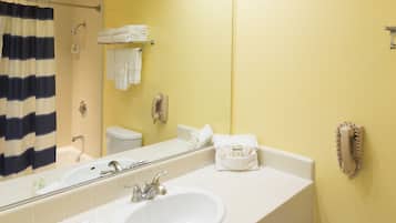 A bathroom with a yellow wall, a white sink, and a large mirror.