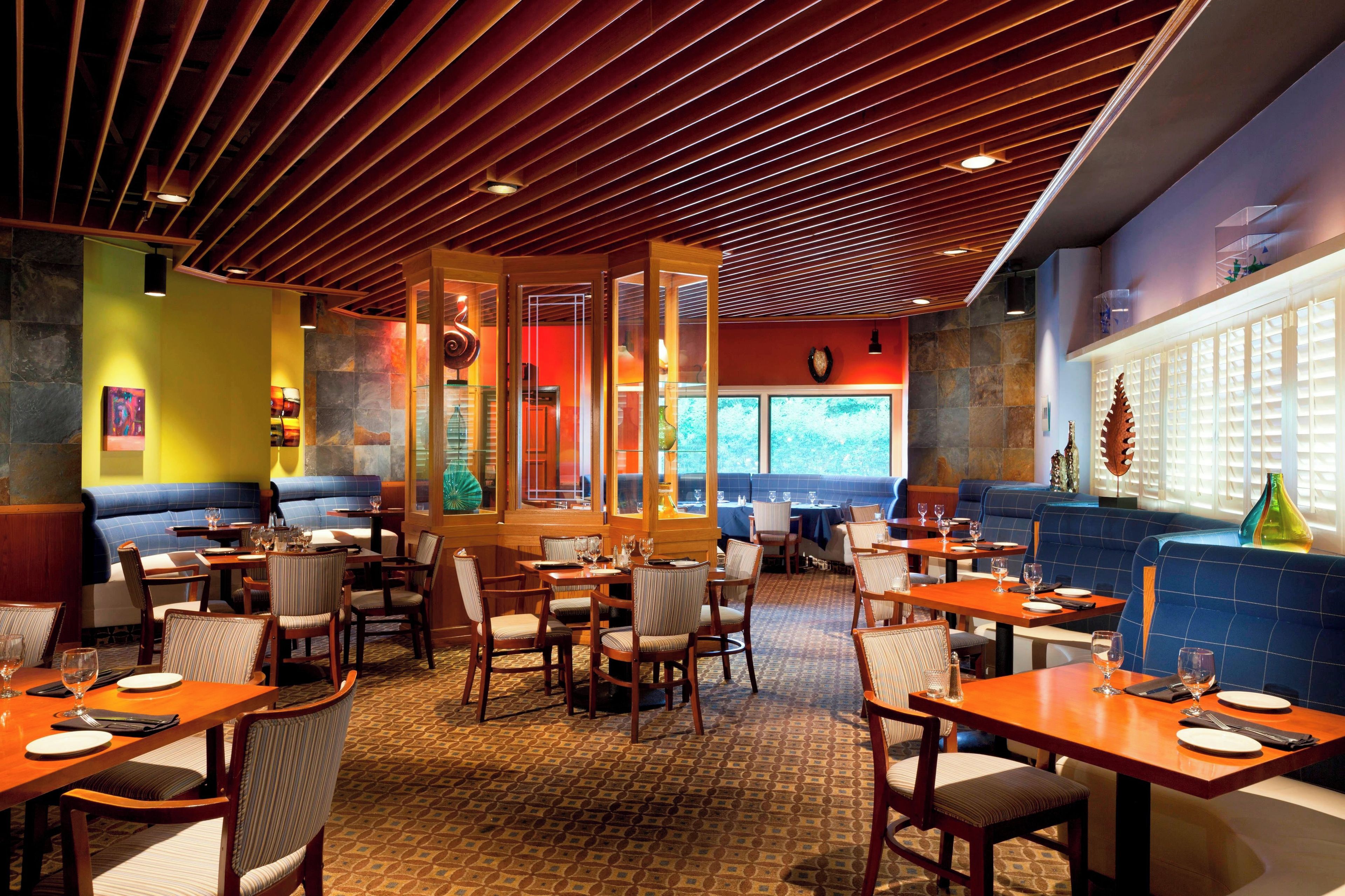 L’intérieur d’un restaurant avec des banquettes, des tables et un sol à motifs.