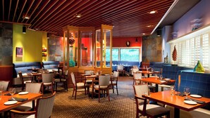 A restaurant with booths and tables, wooden ceiling, and large windows. - Four Points by Sheraton Bakersfield (Bakersfield)