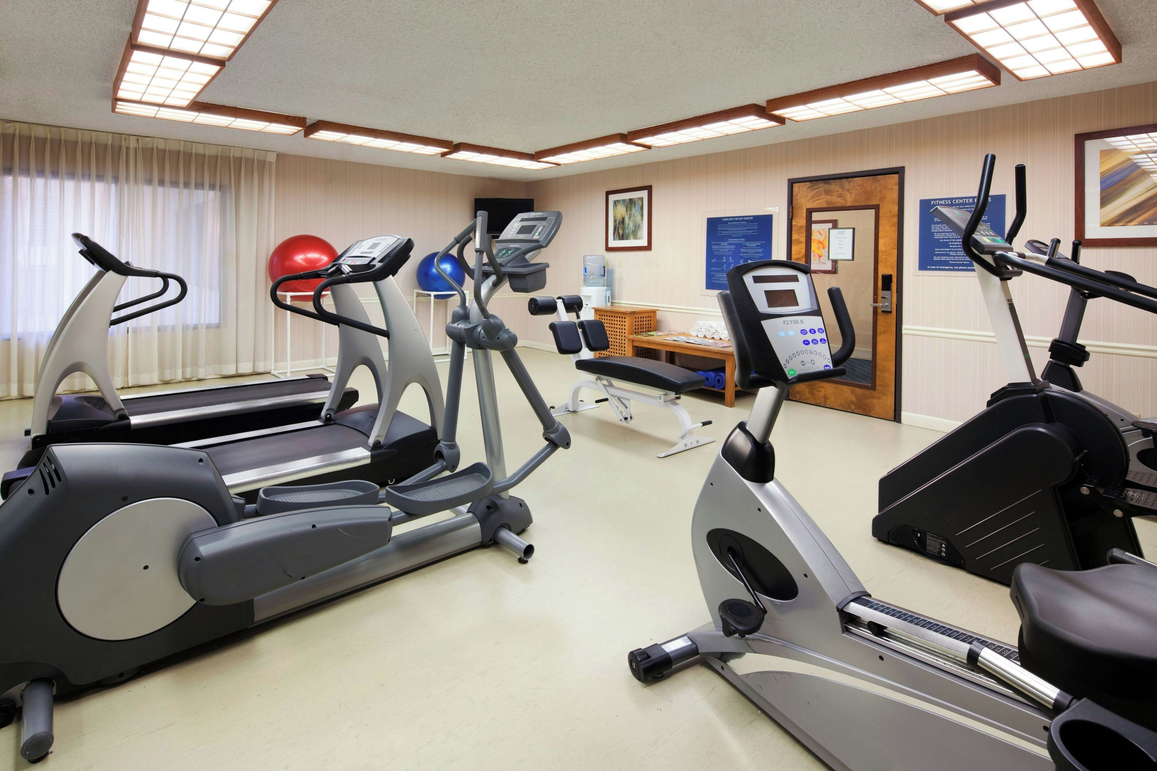 Centro de ginástica com esteiras, elípticos e bolas de exercício.