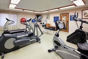 Een fitnessruimte met loopbanden, elliptische trainers en fitnessballen.