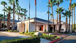 A hotel entrance with palm trees, a flag, and a signboard. - Four Points by Sheraton Bakersfield (Bakersfield)