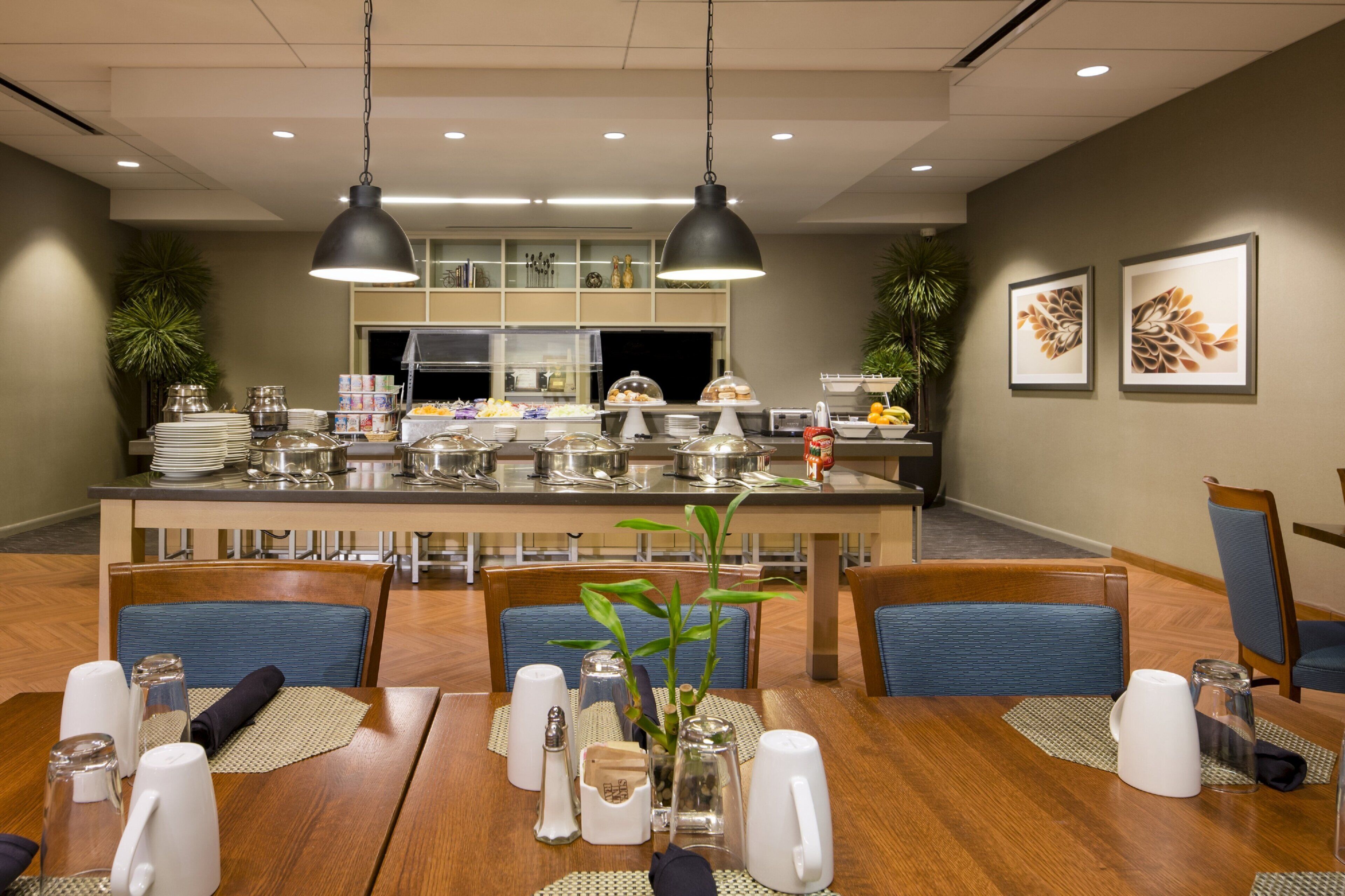 A dining area with a long table, chairs, and a buffet in the background.