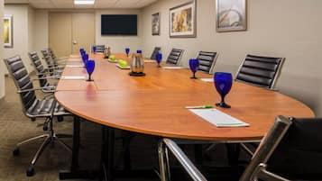 A conference room with a long table, chairs, and a flat-screen TV on the wall.