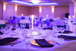 Una mesa de banquete dispuesta con cristalería, platos y cubiertos, con un candelabro como centro de mesa.