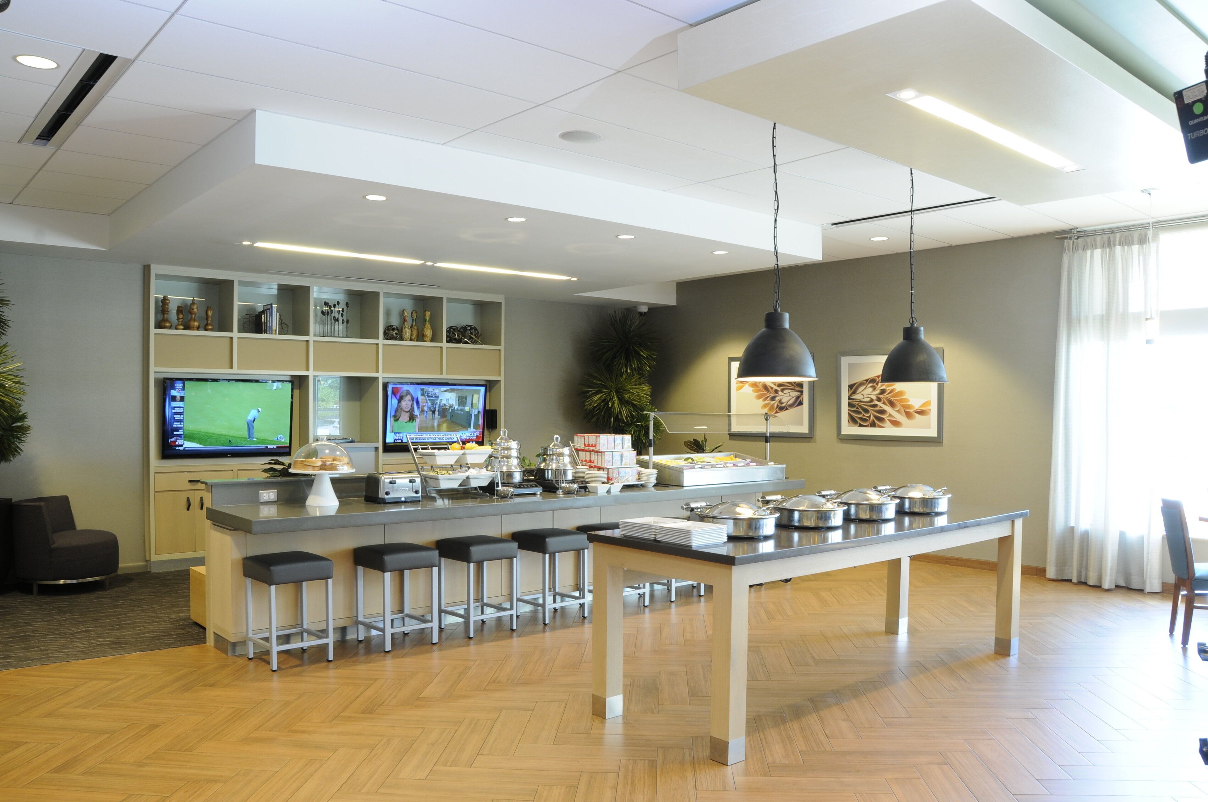 Cocina moderna con una isla central, taburetes de bar y un televisor mostrando un partido de golf.