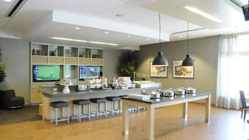 Cocina moderna con una isla central, taburetes de bar y un televisor mostrando un partido de golf.