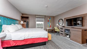 A hotel room with a bed, desk, TV, and storage unit.