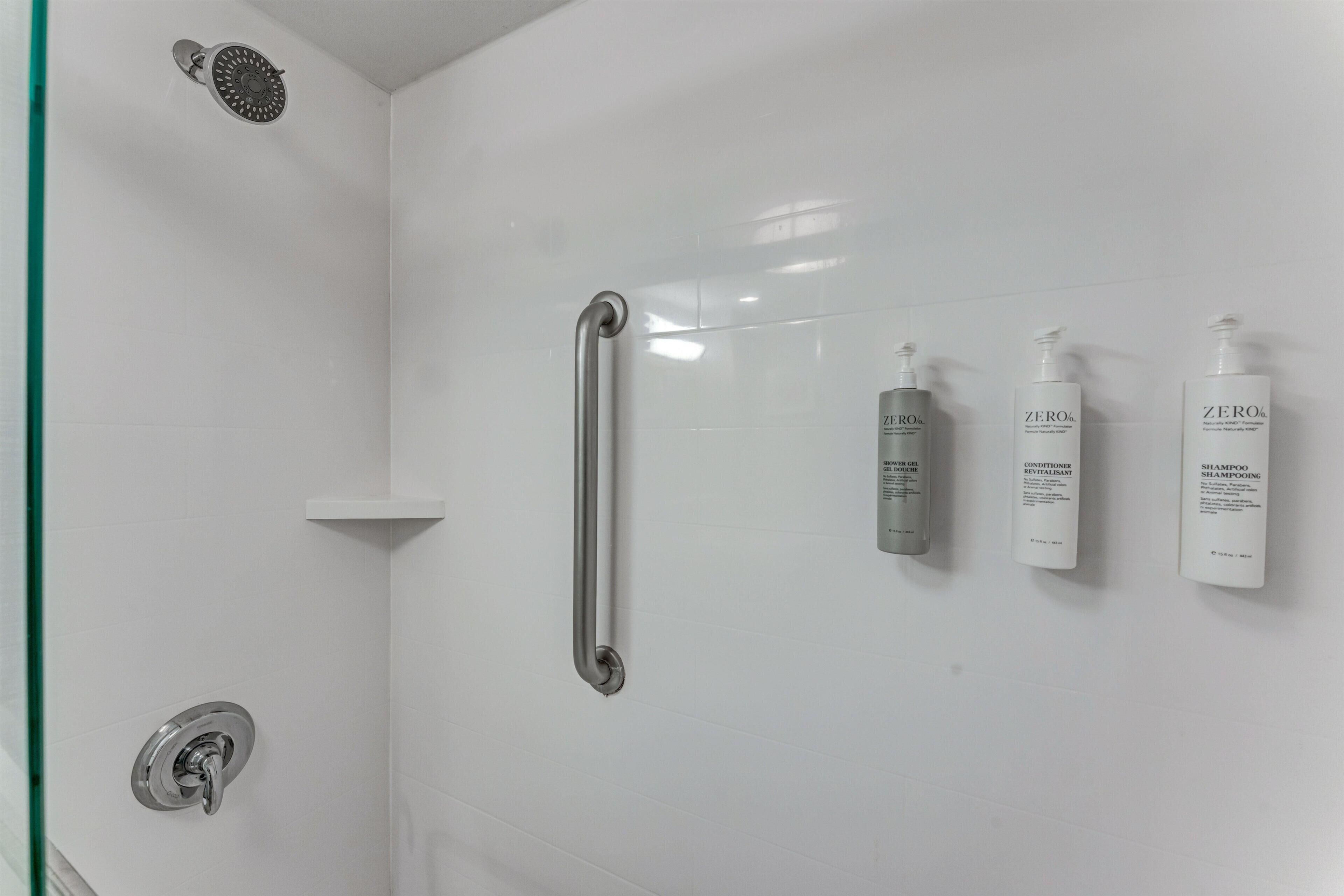 Area doccia con soffione a mano, barra di sostegno e tre flaconi di shampoo e balsamo ZERO%.