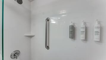 Area doccia con soffione a mano, barra di sostegno e tre flaconi di shampoo e balsamo ZERO%.