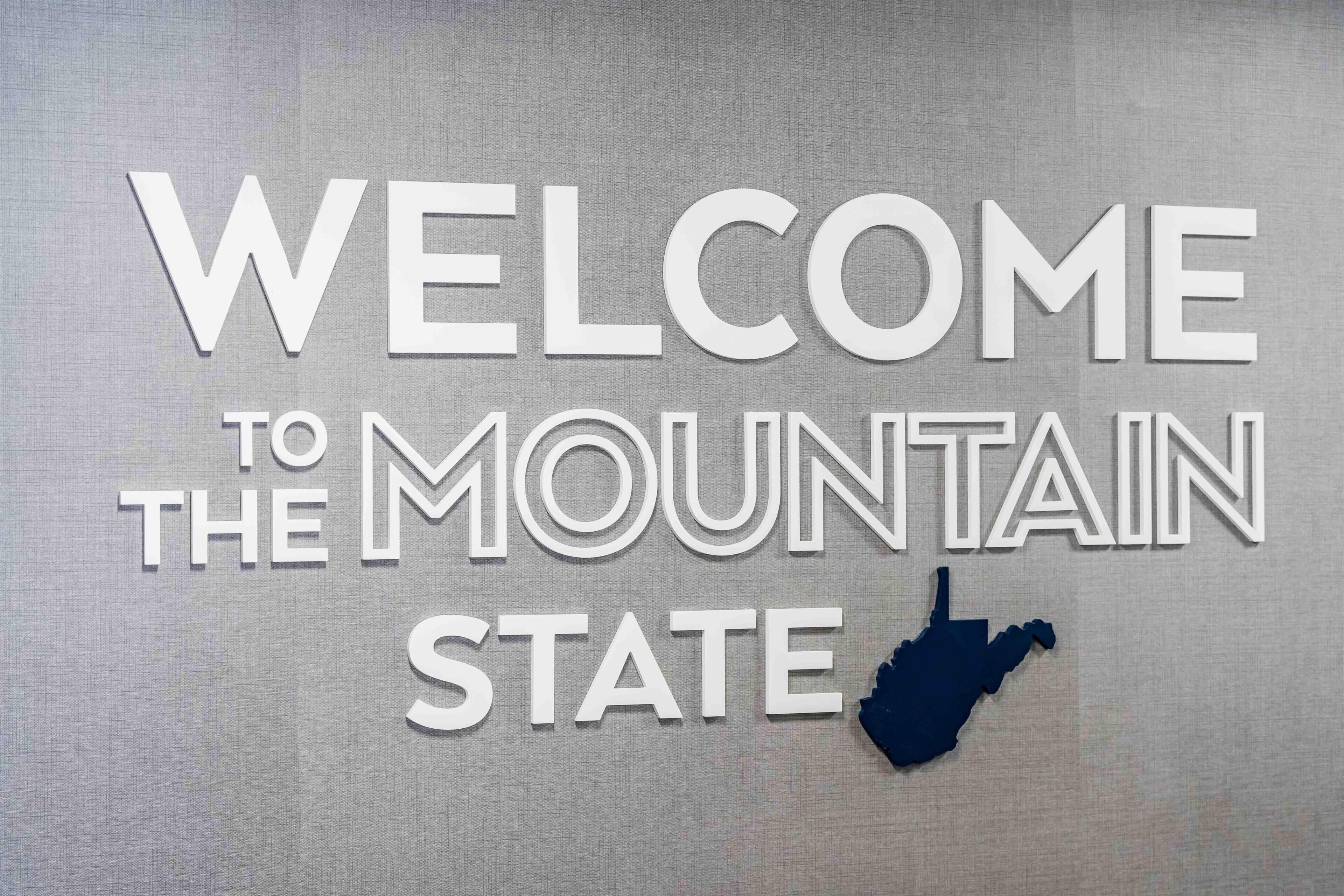 A welcome sign for Mountain State with a silhouette of the state.