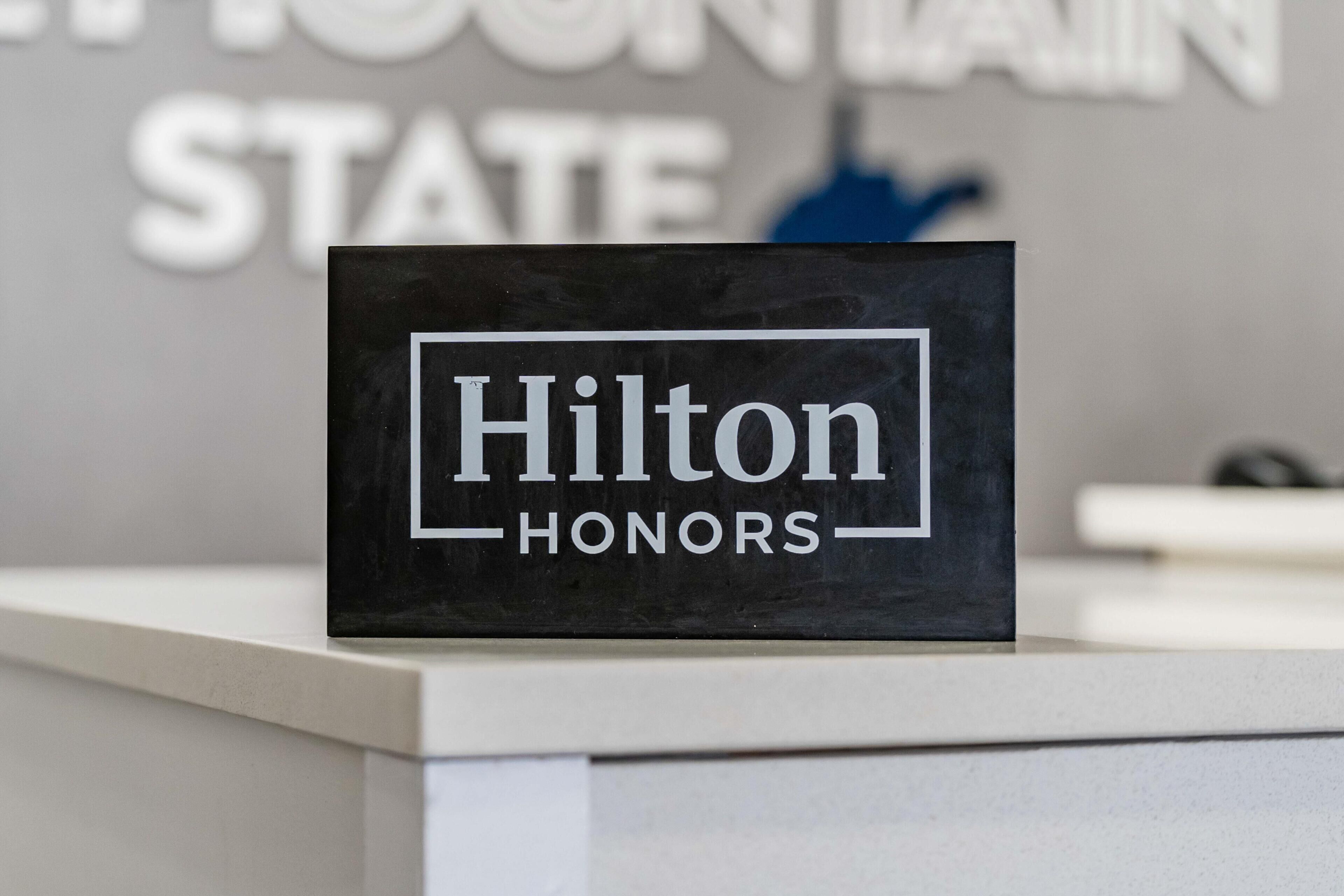Een zwart bord met 'Hilton HONORS' op een witte achtergrond.