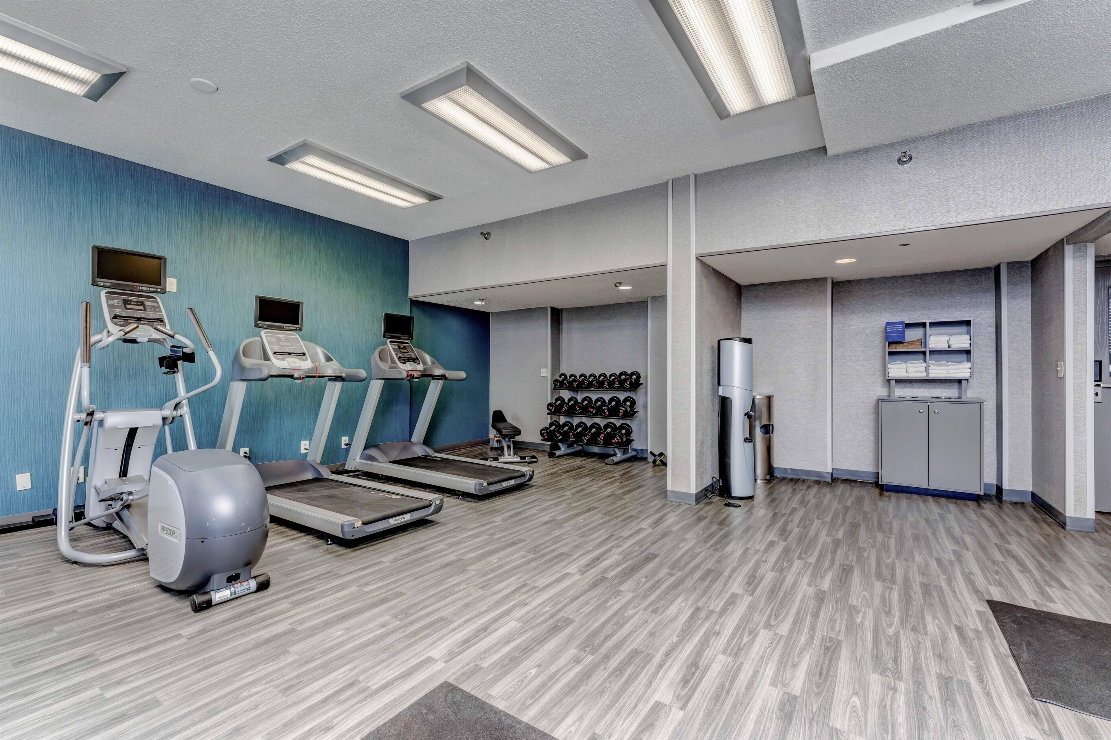 A gym with treadmills, an elliptical, and a wall-mounted TV.