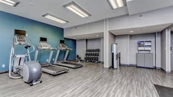 A gym with treadmills, an elliptical, and a wall-mounted TV.