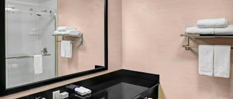 Un baño moderno con un lavamanos negro, un espejo grande y una ducha con cerramiento de vidrio.
