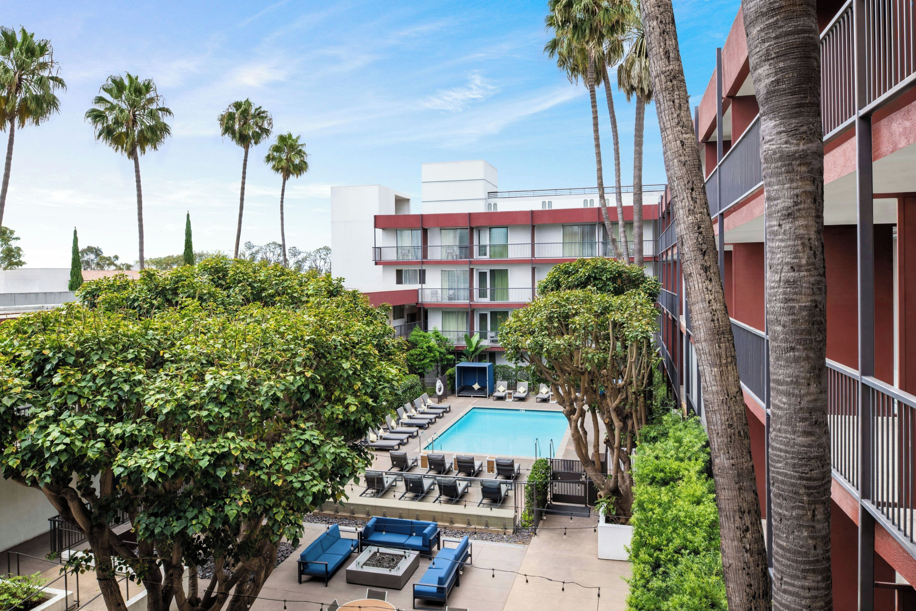 A pool area with lounge chairs and a building with balconies in the background.