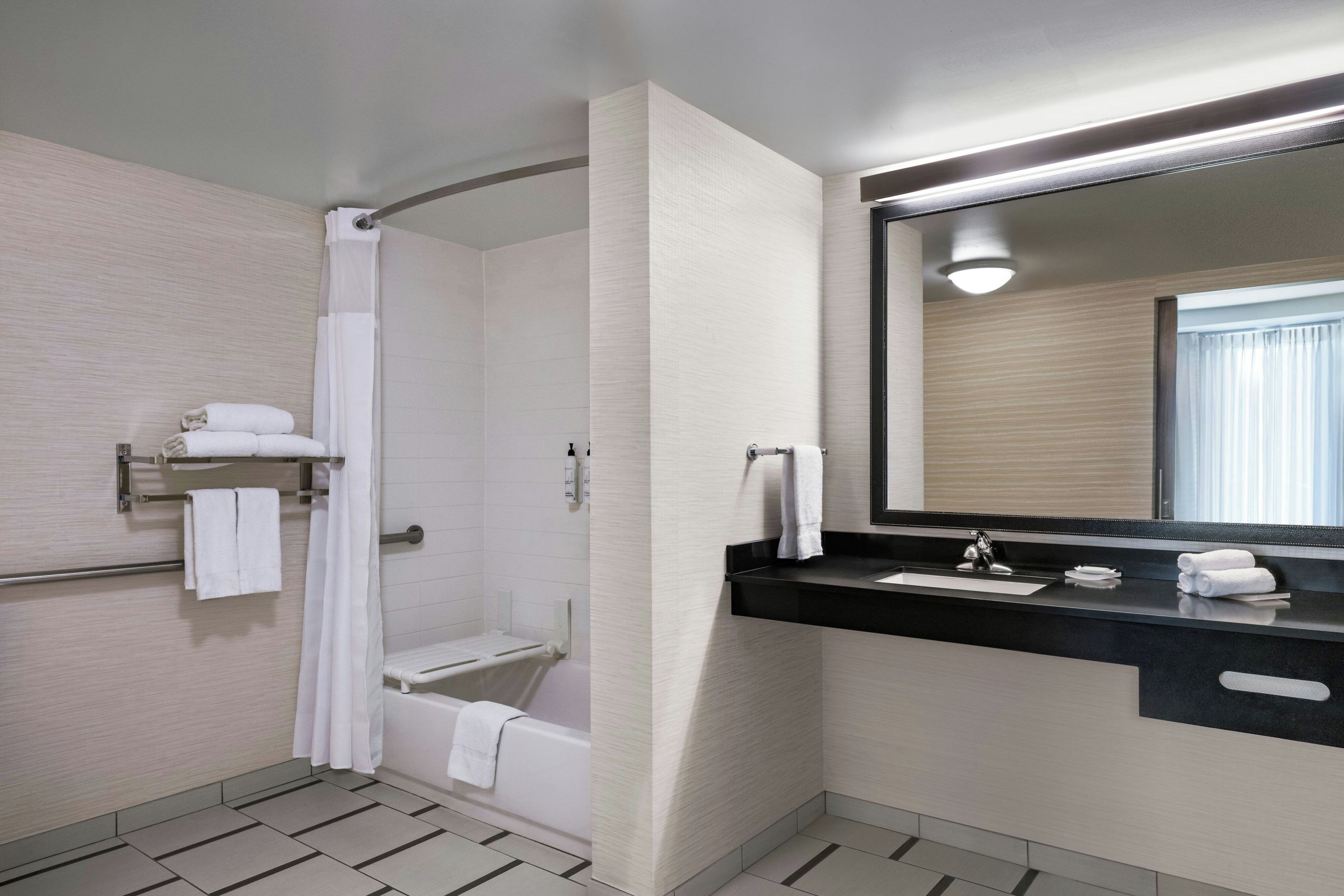 Ein modernes Badezimmer mit Dusche, Badewanne, Waschtisch mit Spiegel und Handtuchhalter.