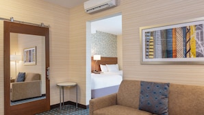 Una habitación de hotel con cama, sofá, una mesita, un espejo y un cuadro en la pared.