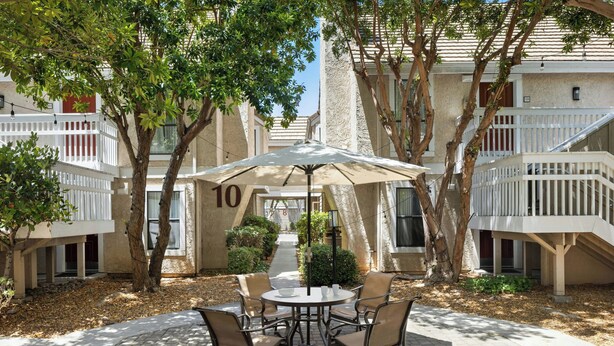 A courtyard with a round table and chairs, surrounded by trees and a white fence. - Residence Inn by Marriott Palo Alto Mountain View (Mountain View)