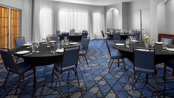 A conference room with round tables, blue chairs, and a patterned carpet.