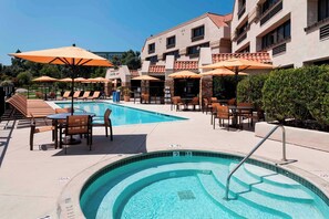 Relax by the pool surrounded by comfortable lounge chairs and shaded tables.