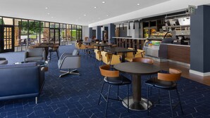 Un moderno vestíbulo de hotel con diversas opciones de asientos, incluyendo sofás y mesas, y una estación de café Starbucks.