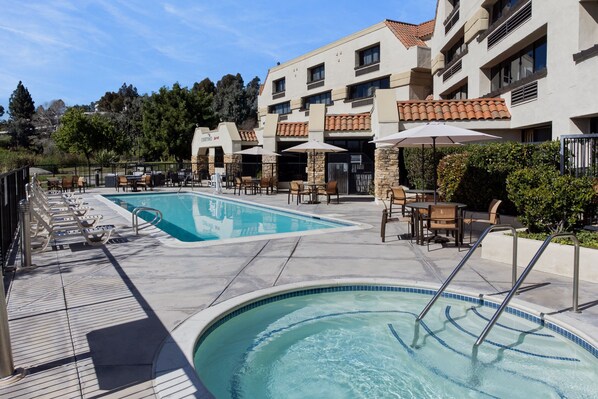 Relax by the rectangular pool surrounded by lounge chairs and umbrellas.