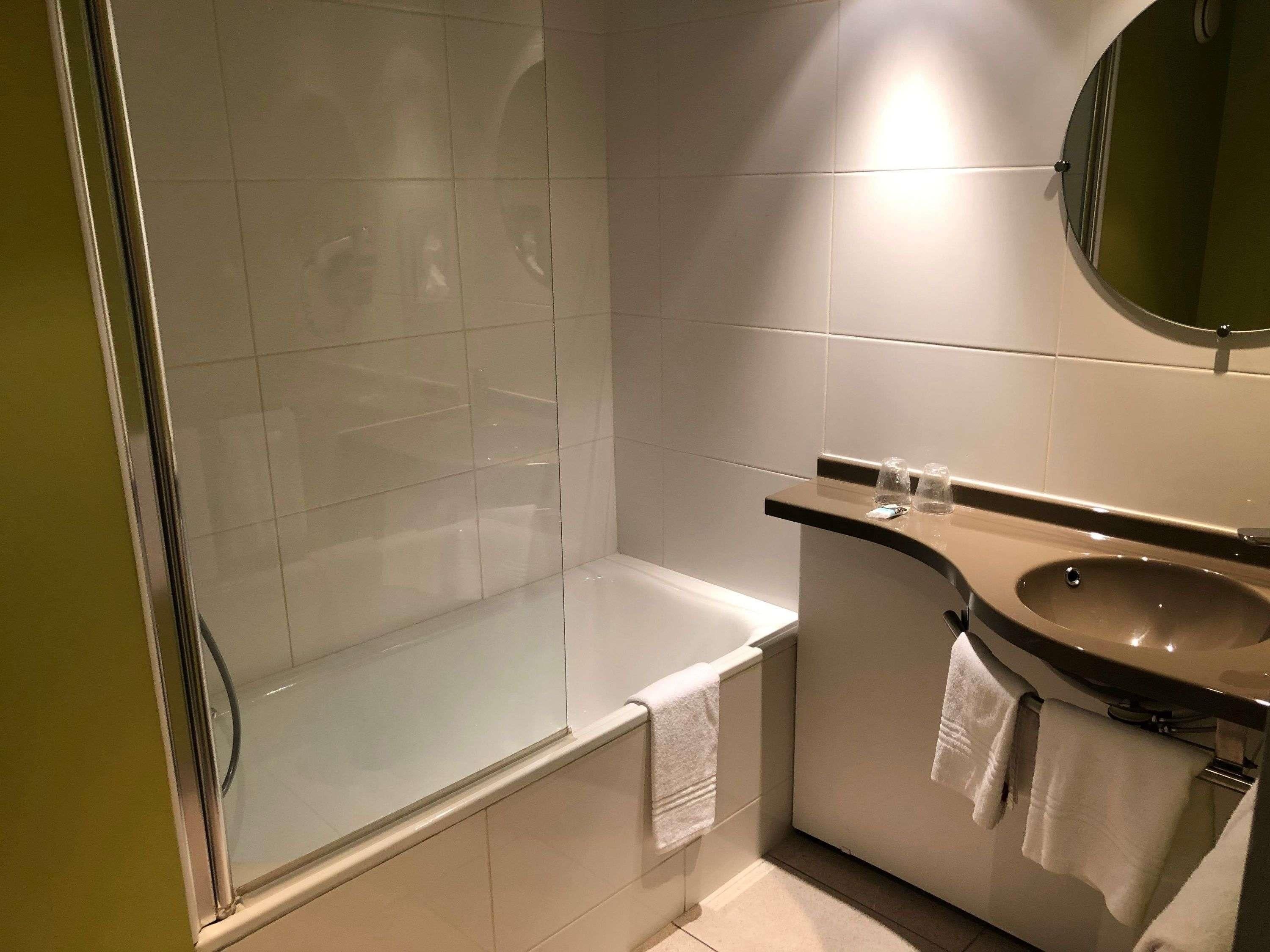 Un baño moderno con cabina de ducha de vidrio, bañera y tocador con lavamanos.