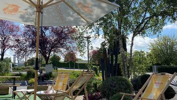 Un espace extérieur aménagé avec des fauteuils et une table, le tout installé sous une pergola.