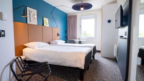 Habitación de hotel con dos camas, un escritorio, una silla, un televisor y una ventana con cortinas.